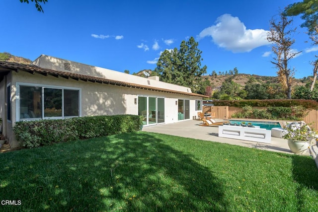 rear view of property featuring a fenced in pool, a patio, and a yard