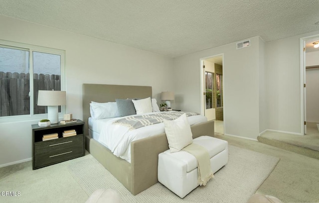 carpeted bedroom featuring a textured ceiling and ensuite bathroom