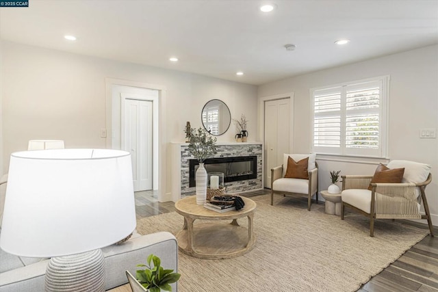 living room with a tiled fireplace and wood-type flooring