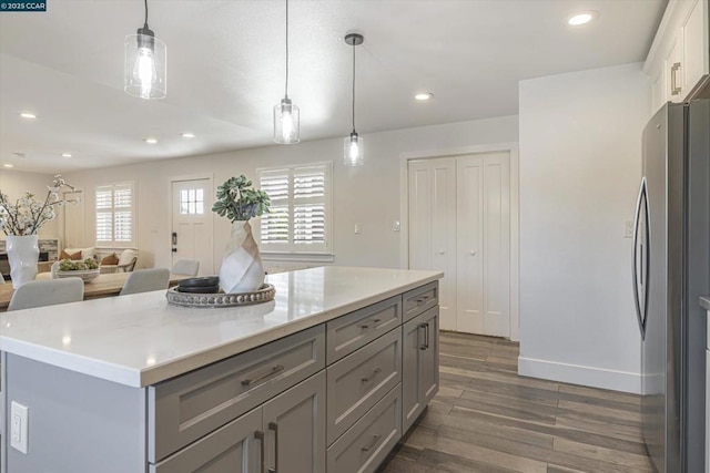 kitchen with white cabinetry, stainless steel refrigerator, a wealth of natural light, pendant lighting, and a center island