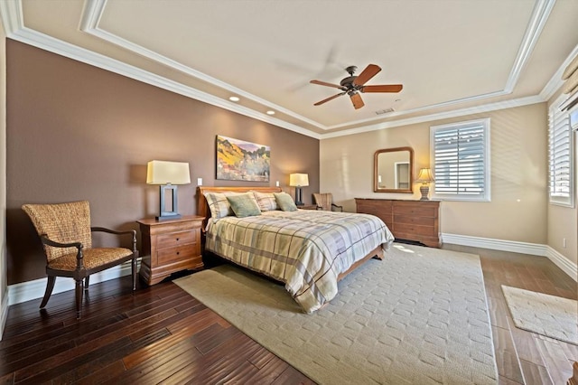 bedroom featuring ornamental molding, dark wood-type flooring, ceiling fan, and a tray ceiling