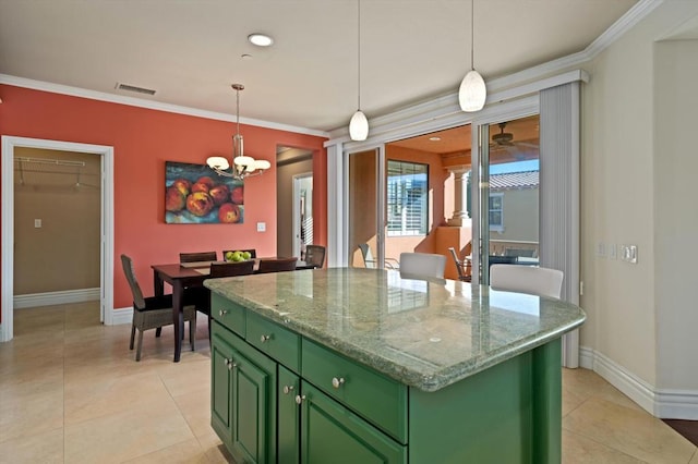 kitchen with green cabinetry, a center island, hanging light fixtures, ornamental molding, and light stone countertops