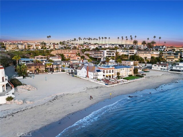 aerial view at dusk with a water view and a view of the beach