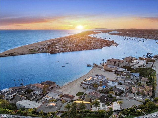 aerial view at dusk with a water view and a view of the beach