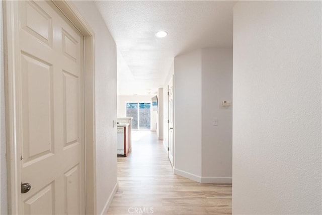 corridor featuring a textured ceiling and light wood-type flooring