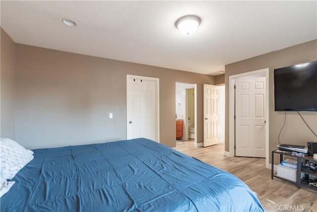 bedroom featuring wood-type flooring and ensuite bath