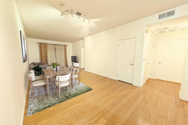 dining room with light hardwood / wood-style floors and rail lighting