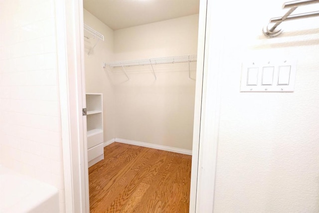 walk in closet with light hardwood / wood-style flooring