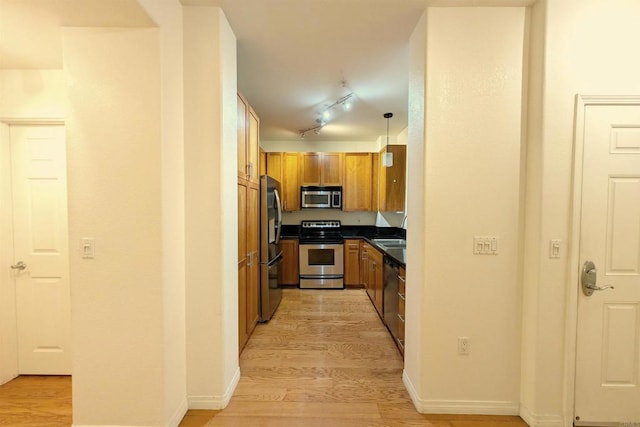 kitchen with light wood-type flooring, appliances with stainless steel finishes, pendant lighting, and track lighting