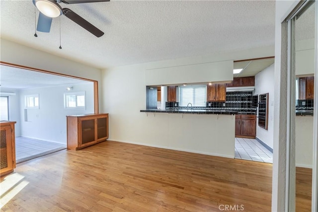 kitchen featuring light hardwood / wood-style flooring, tasteful backsplash, a kitchen bar, tile countertops, and kitchen peninsula