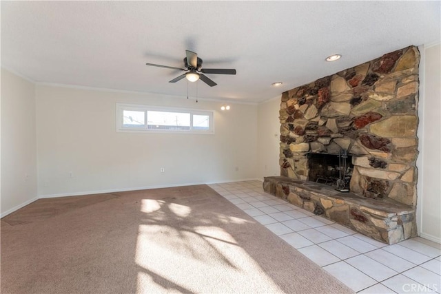 unfurnished living room with ceiling fan, ornamental molding, a stone fireplace, and light tile patterned floors