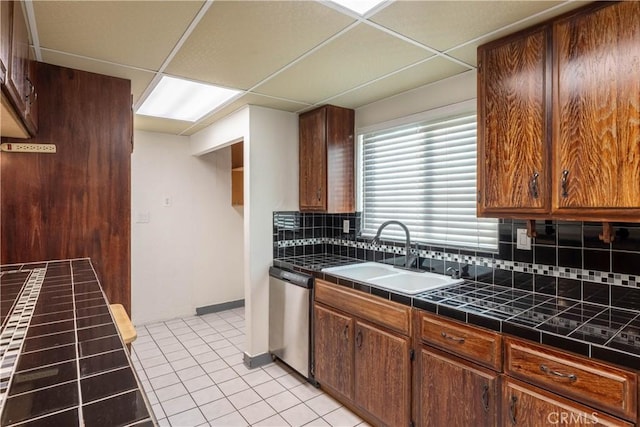 kitchen with sink, a paneled ceiling, dishwasher, backsplash, and light tile patterned flooring