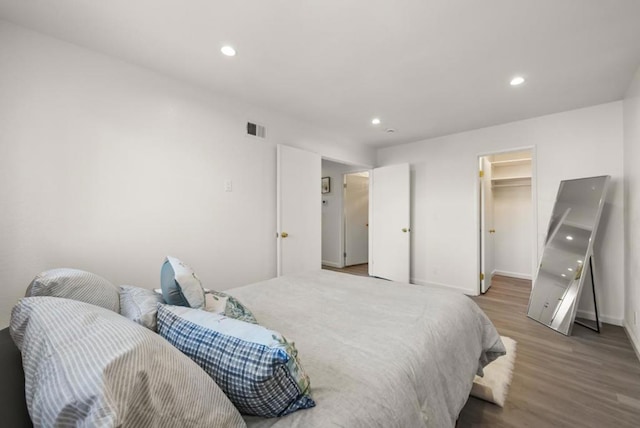 bedroom with hardwood / wood-style flooring, a closet, and a walk in closet