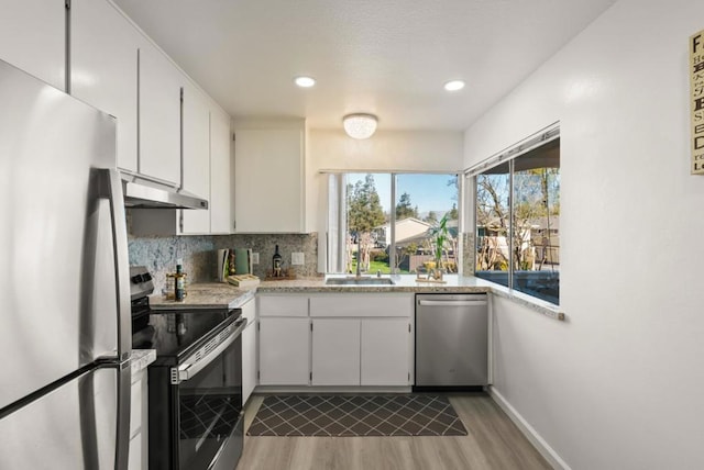 kitchen featuring backsplash, sink, white cabinetry, light wood-type flooring, and stainless steel appliances