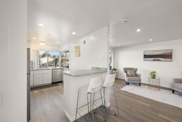 kitchen featuring white cabinetry, wood-type flooring, stainless steel appliances, and kitchen peninsula