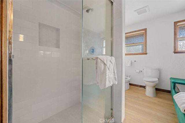 bathroom featuring a shower with shower door, a bidet, toilet, and hardwood / wood-style floors