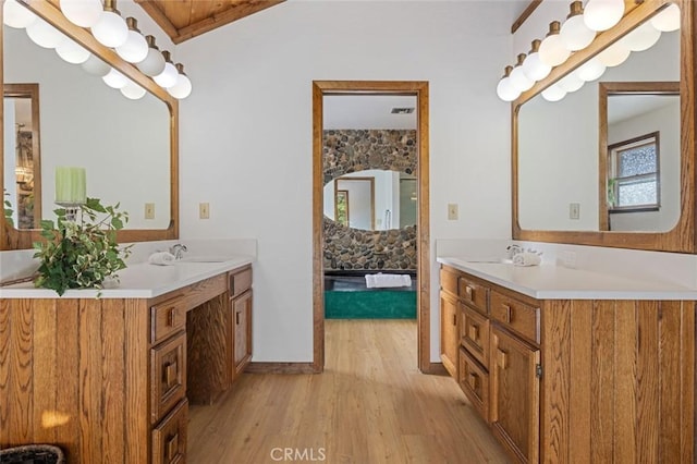 bathroom with wood-type flooring, vanity, and lofted ceiling