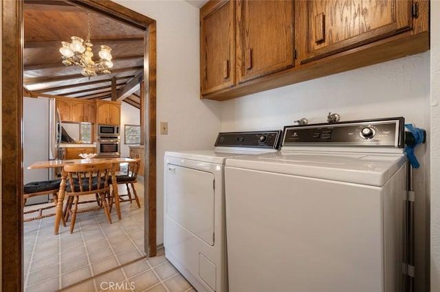 laundry area with cabinets, light tile patterned floors, washer and clothes dryer, and an inviting chandelier