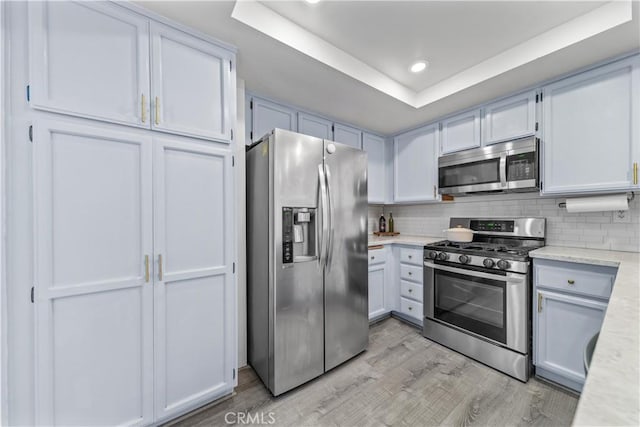 kitchen featuring white cabinetry, stainless steel appliances, and a raised ceiling