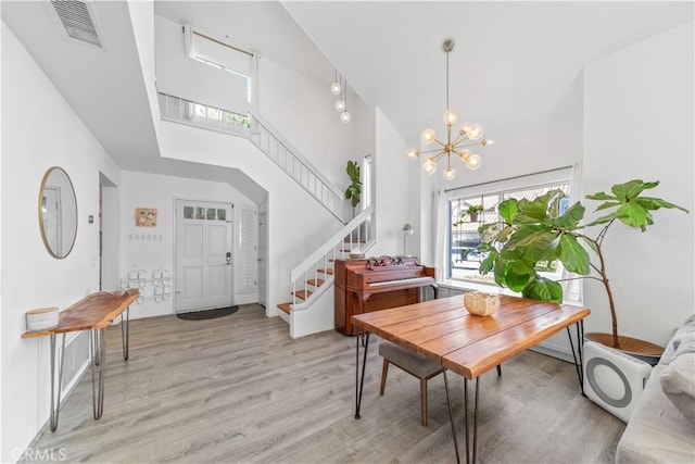 dining room with a high ceiling, a chandelier, and light wood-type flooring