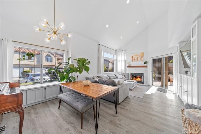 living room with high vaulted ceiling, light wood-type flooring, and plenty of natural light