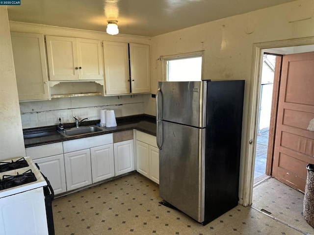 kitchen featuring sink, white cabinets, stainless steel fridge, decorative backsplash, and white range with gas cooktop