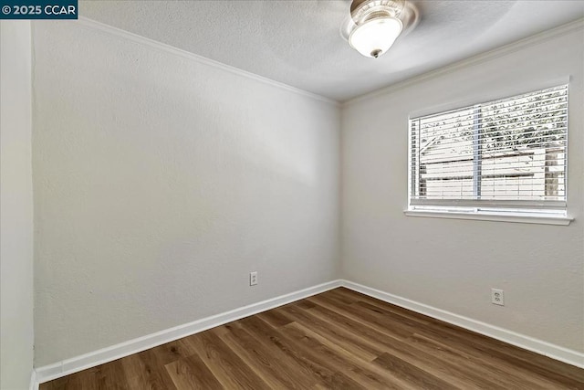 spare room featuring dark wood-type flooring and crown molding