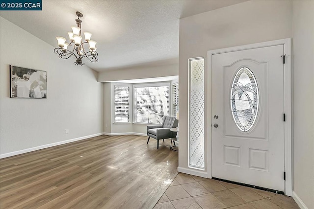 foyer with light hardwood / wood-style floors, lofted ceiling, and a notable chandelier