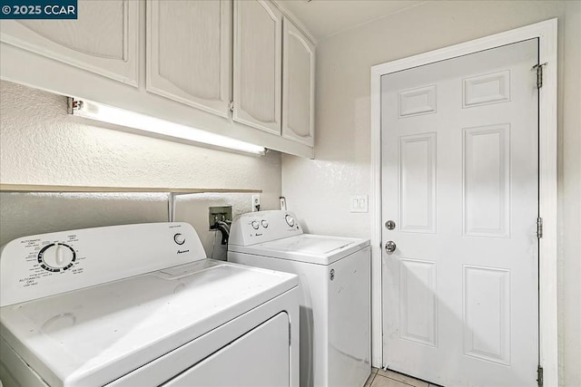 clothes washing area featuring light tile patterned floors, washing machine and clothes dryer, and cabinets