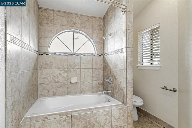 bathroom featuring toilet, tile patterned floors, and tiled shower / bath