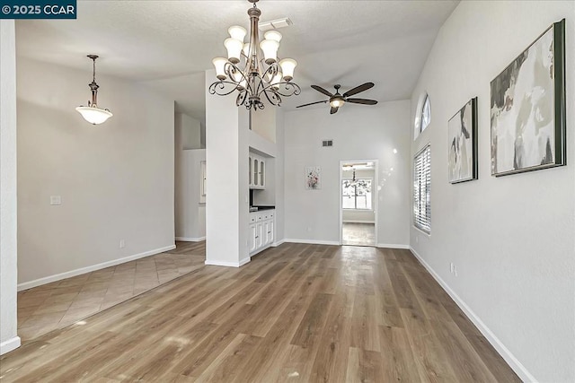 unfurnished living room with ceiling fan with notable chandelier and wood-type flooring