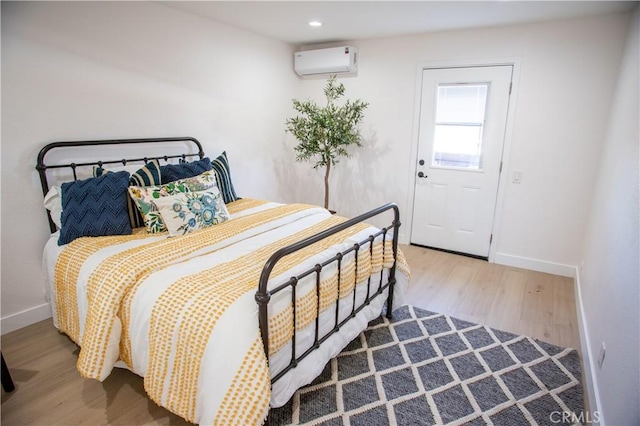 bedroom with a wall unit AC and hardwood / wood-style flooring