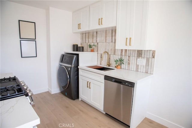 kitchen with white cabinets, washer / dryer, stainless steel appliances, decorative backsplash, and sink