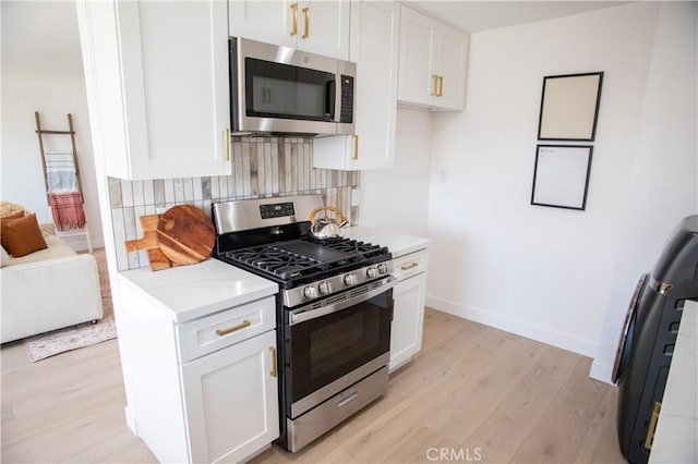 kitchen featuring white cabinets, light wood-type flooring, backsplash, and stainless steel appliances