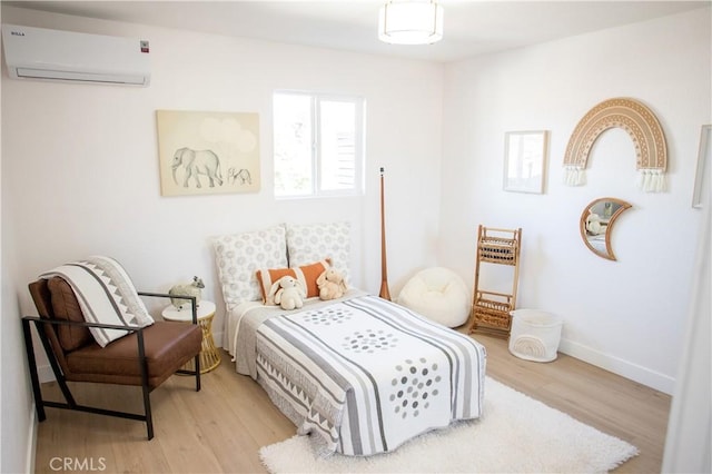 bedroom with a wall mounted AC and light wood-type flooring