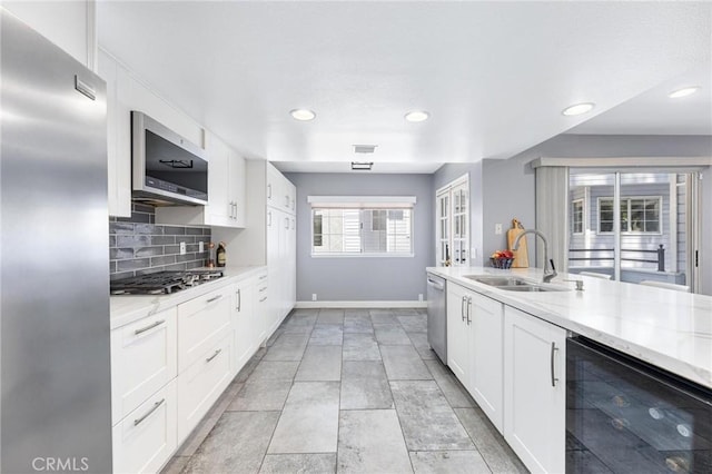 kitchen featuring white cabinets, stainless steel appliances, tasteful backsplash, wine cooler, and sink