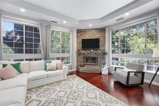 living room with a fireplace, dark hardwood / wood-style floors, and a tray ceiling