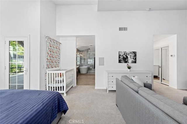 bedroom with a high ceiling, connected bathroom, a closet, and light carpet