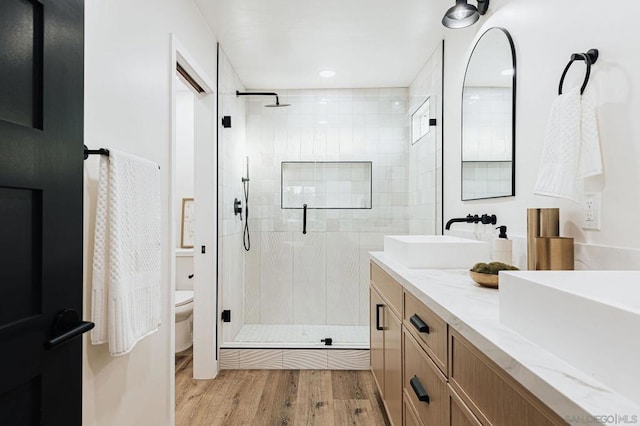 bathroom featuring hardwood / wood-style flooring, toilet, walk in shower, and vanity