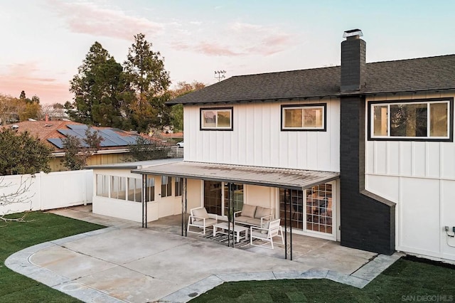 back house at dusk featuring a sunroom and a patio