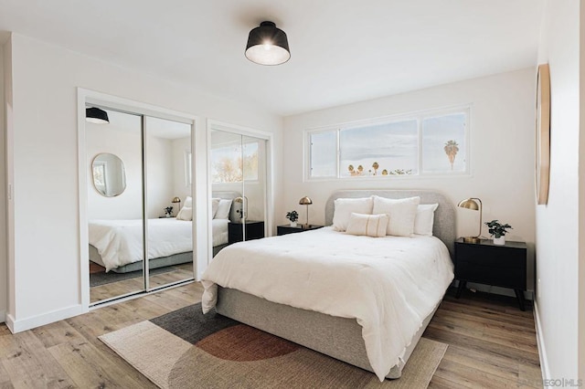 bedroom featuring multiple closets and light hardwood / wood-style floors