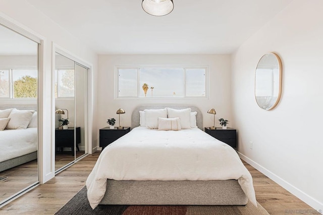 bedroom with multiple closets, multiple windows, and light hardwood / wood-style flooring