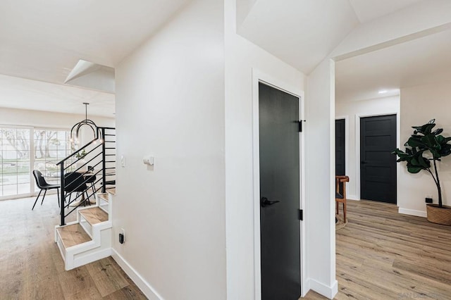 hallway featuring a chandelier, lofted ceiling, and light hardwood / wood-style flooring