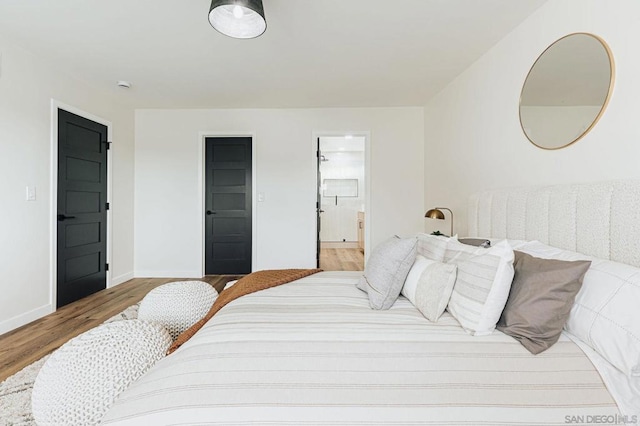 bedroom featuring connected bathroom and light hardwood / wood-style flooring