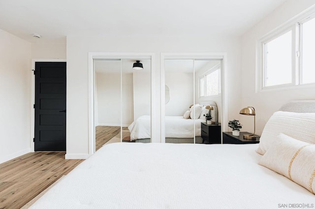 bedroom featuring two closets, multiple windows, and light wood-type flooring