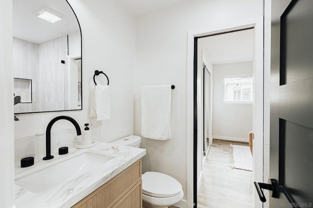 bathroom featuring toilet, walk in shower, hardwood / wood-style floors, and vanity