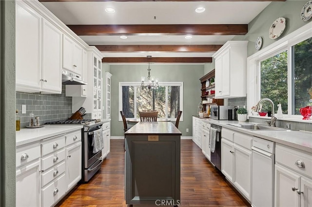 kitchen featuring stainless steel appliances, a center island, a notable chandelier, white cabinets, and beamed ceiling