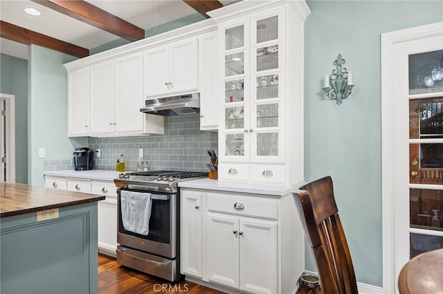 kitchen with dark wood-type flooring, white cabinetry, decorative backsplash, stainless steel range with gas cooktop, and beam ceiling