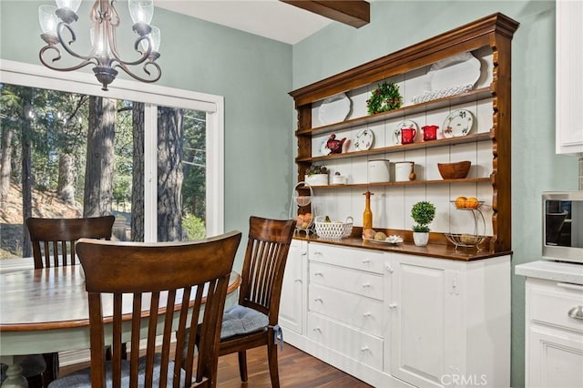 dining room with an inviting chandelier, a wealth of natural light, dark hardwood / wood-style flooring, and beamed ceiling