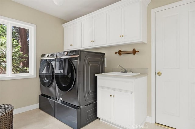 washroom with washer and dryer, sink, a wealth of natural light, and cabinets